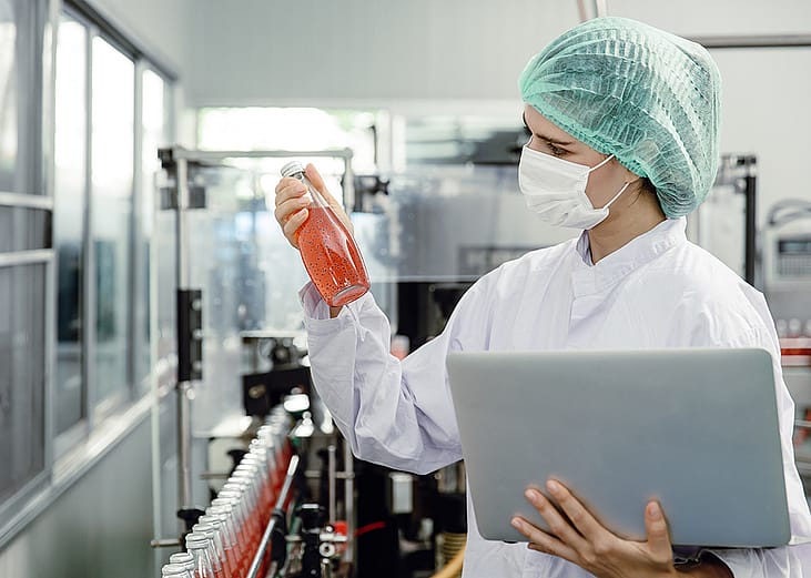 A food inspector specialist checking a bottle drink's mix and seal during the final stages of production in a factory.