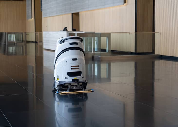 An automated floor robot cleaning the lobby floor of a modern office.