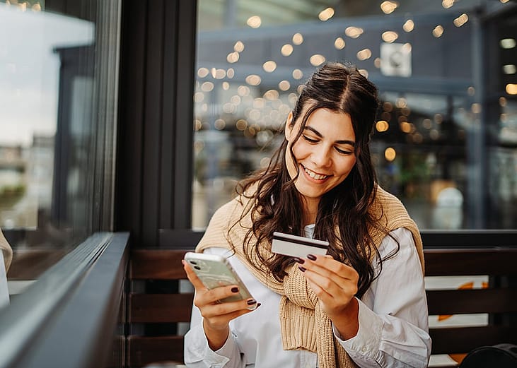 A happy young woman using a credit card to purchase online.