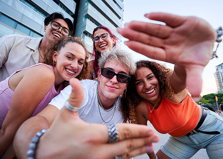 A group of Gen Z friends taking a selfie together outdoors.