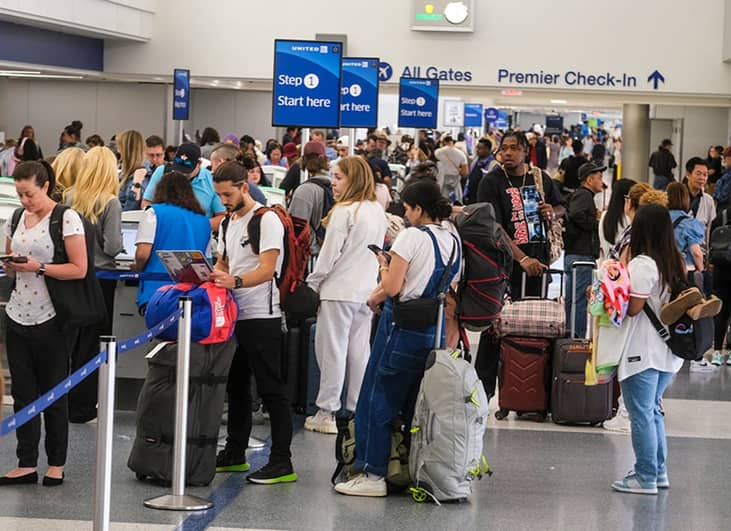 Travelers waiting in line before the check-in counters at an international airport.