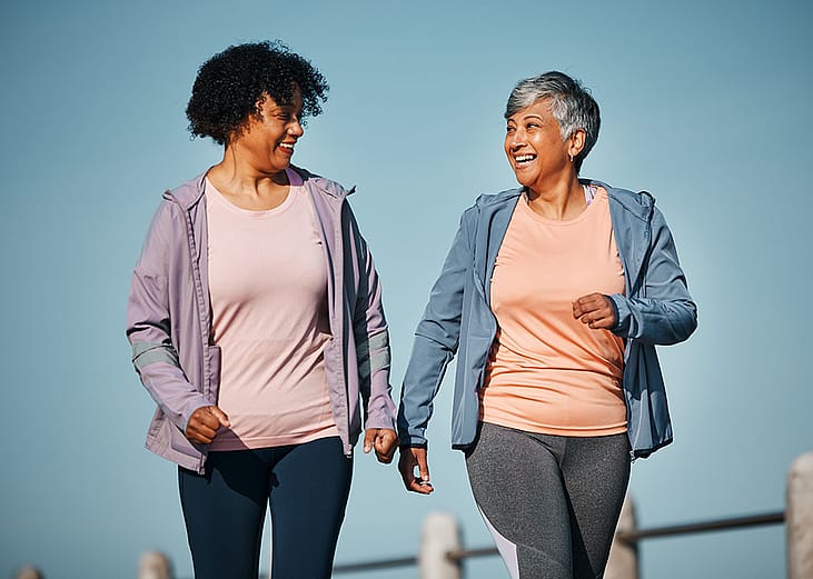 Two senior women talking a walk together outdoors.