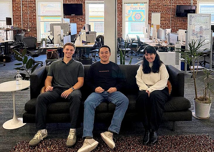Kevin Wu, the CEO of Leaping AI sits on a black couch with two employees who are forward deployed engineers.