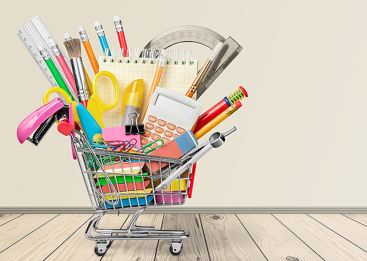 A mini shopping cart filled with different school materials and supplies.