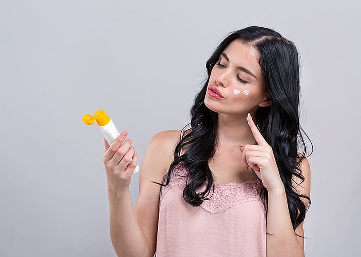 A young woman putting on sunscreen.
