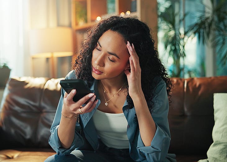 A woman reading a text and experiencing a headache.