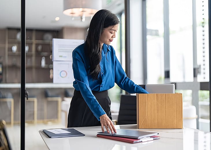 A female employee putting work items in a box for her last day at work.