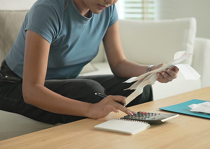 A woman at home calculating bills and expenses.