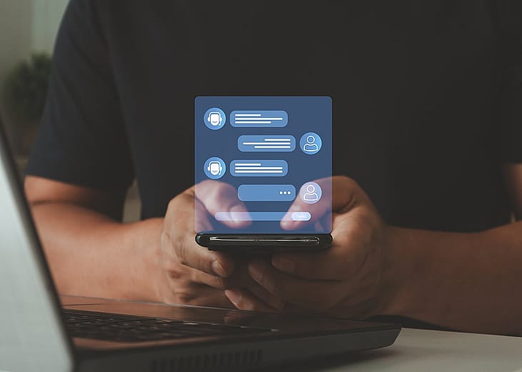 A person using a smartphone with a holographic AI-driven chatbot messaging interface for services concerns.