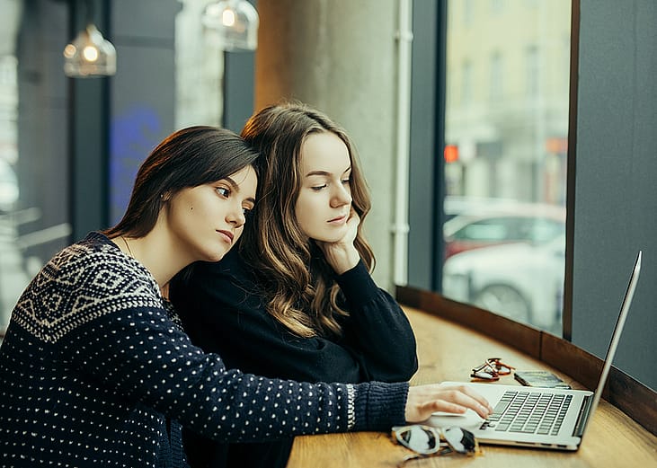 Young adults checking AI digital platforms for relationship advice from a laptop.
