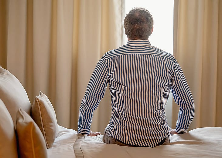 Man sitting still on a hotel bed