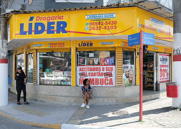 A yellow storefront of Drogaria Líder, a Brazilian drugstore situated on the street corner.