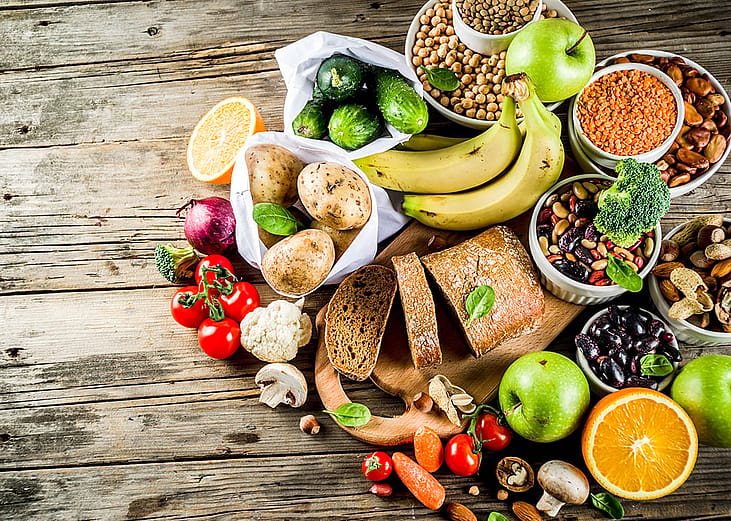 A selection of fresh and high-fiber foods, fruits, and vegetables laid in a wooden table.