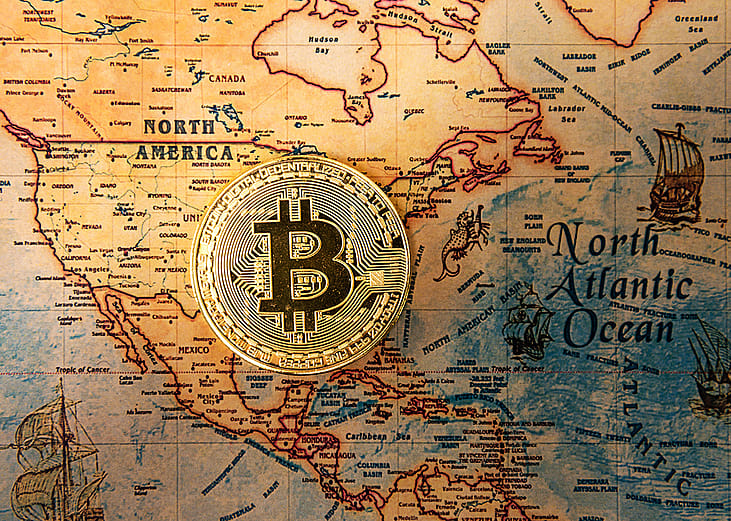 A crypto currency bitcoin symbol centered on an ancient map of North America and North Atlantic ocean.