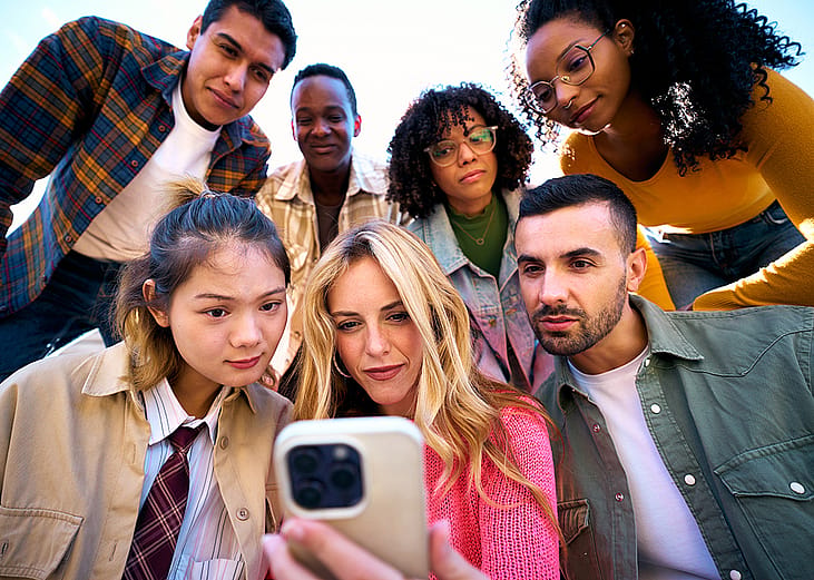 A group of friends looking together at something in a phone.
