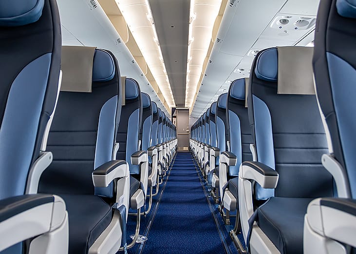 An interior cabin of an empty commercial aircraft lining a central aisle.