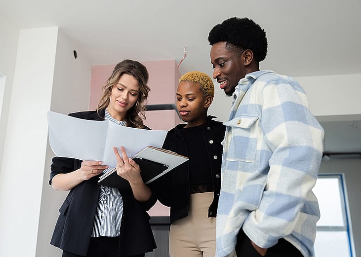 A young couple reviewing documents together with a property consultant.