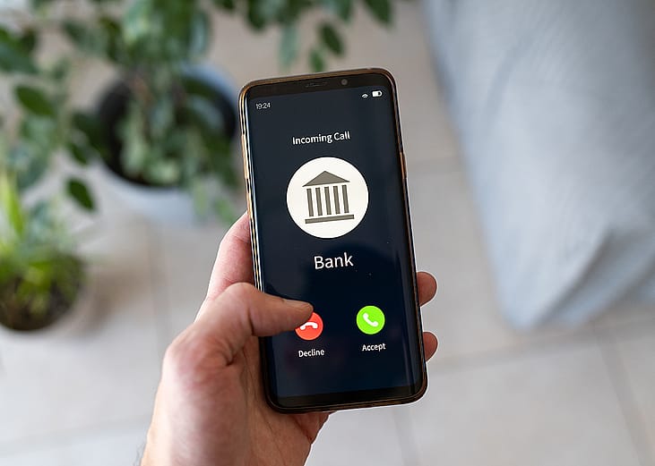 Hand holding a smartphone with an incoming call from a bank