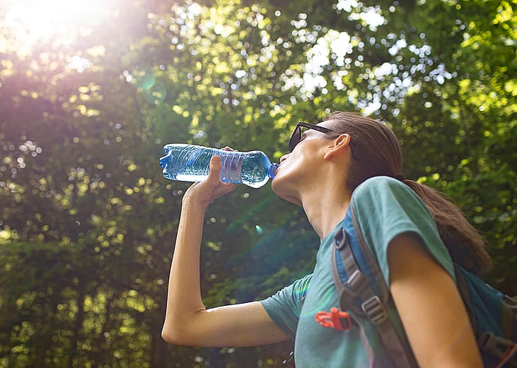 A person drinking water during a stroll in the park. 