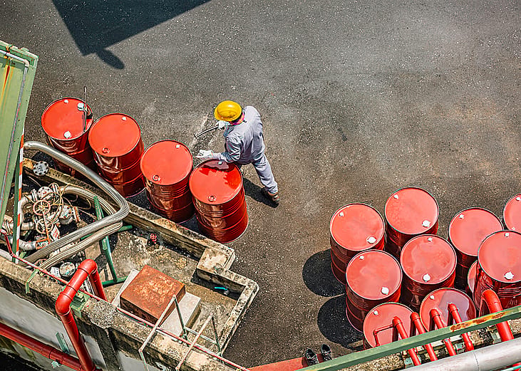 Top view of a male worker checking barrels of oil.