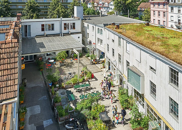 Aerial view of the courtyard of Gundeldinger Feld in Basel, Switzerland, a former industrial site turned into a thriving neighborhood center.