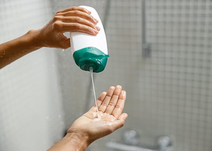 A person pouring a body wash gel on her hand during shower time.