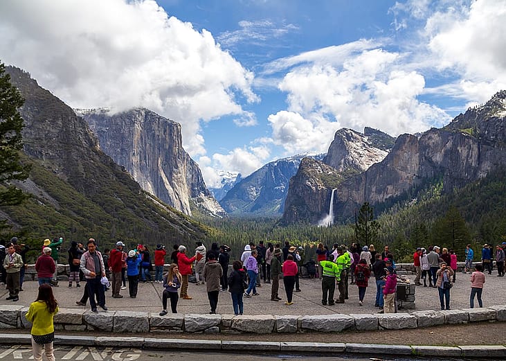 Tourists enjoying the scenic landscape of mountains and waterfalls in Yosemite National Park, United States.