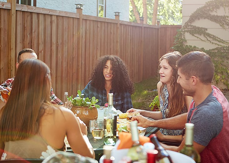 A happy group of friends sharing a meal in a backyard.