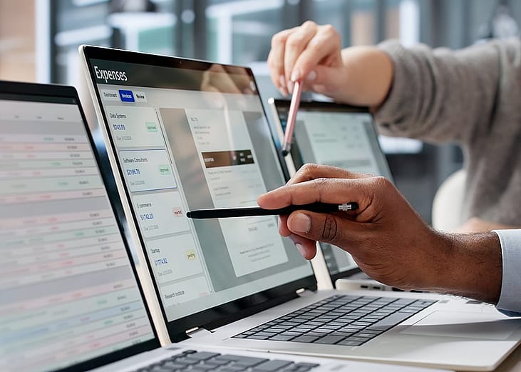 Finance employees reviewing expenses on a computer screen.