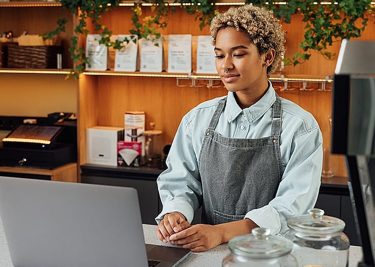 A café owner reviewing business insurance options on her laptop during a short break.