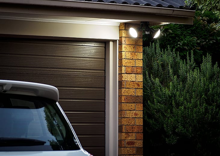 A view of a home's garage door at night with security lights.