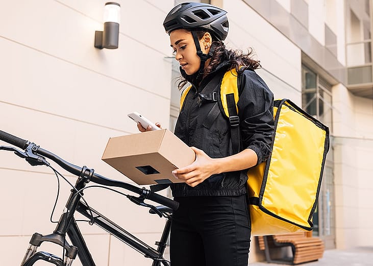 A delivery worker contacting a recipient outside, while holding a parcel package. package