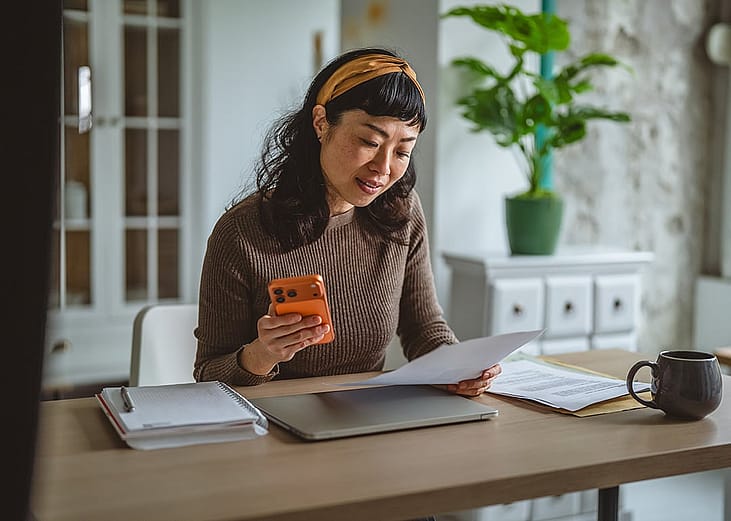 A woman at home reviewing expense documents