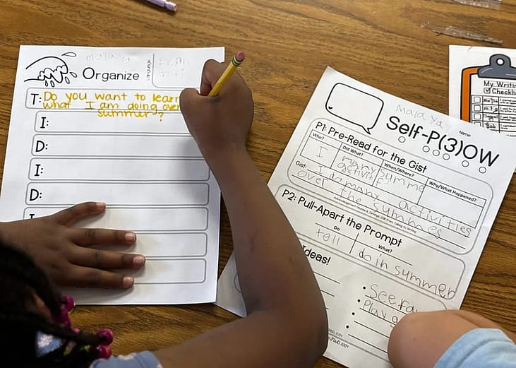 A first grader at Sand Creek Elementary fills out a worksheet to help organize thoughts before writing a paragraph about her summer plans. The Douglas County School District adopted a method of teaching writing that emphasizes structure and planning.