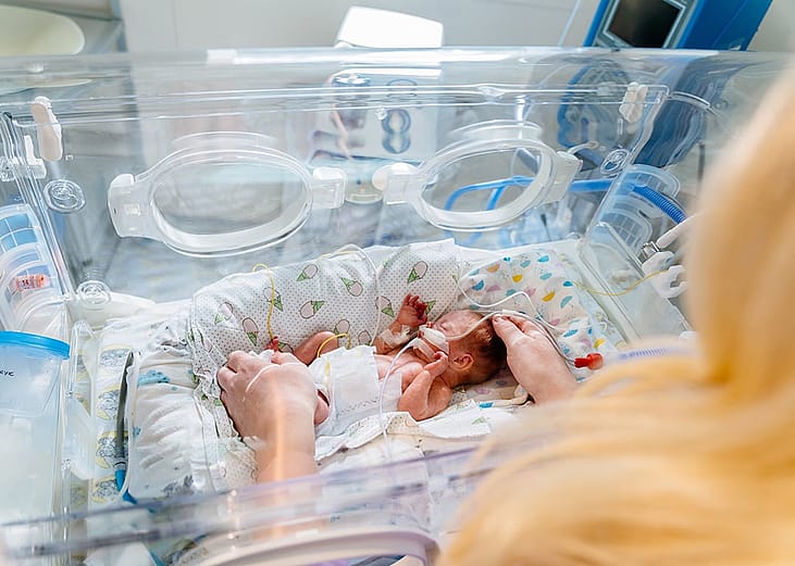 A mother looking at her baby in an incubator.