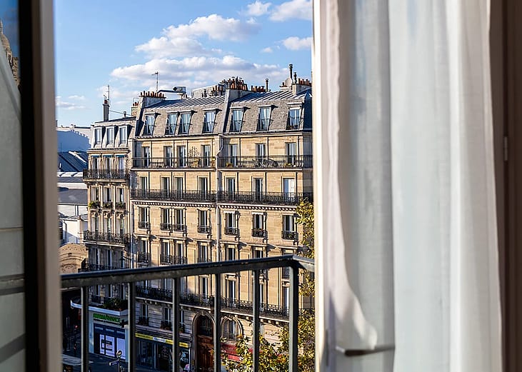 A balcony window overlooking a classic residential building in Paris, France.