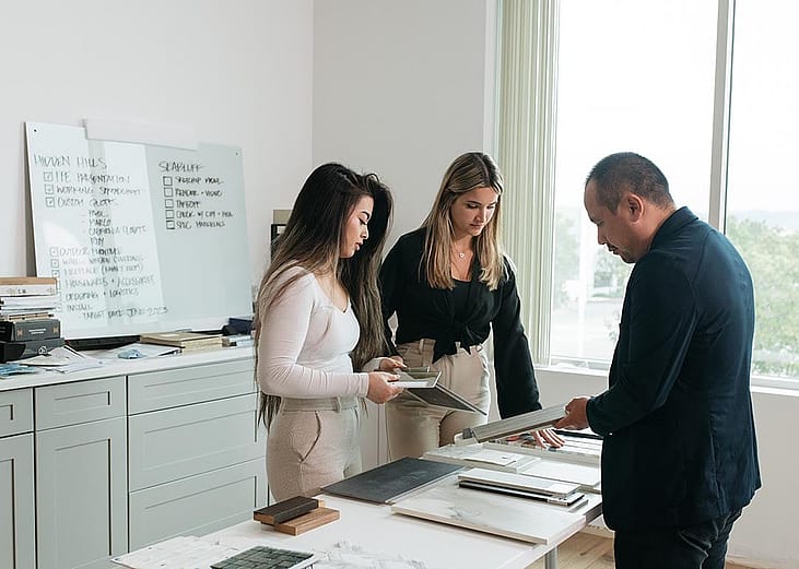 A client and interior designers reviewing physical samples and material selections in a studio.