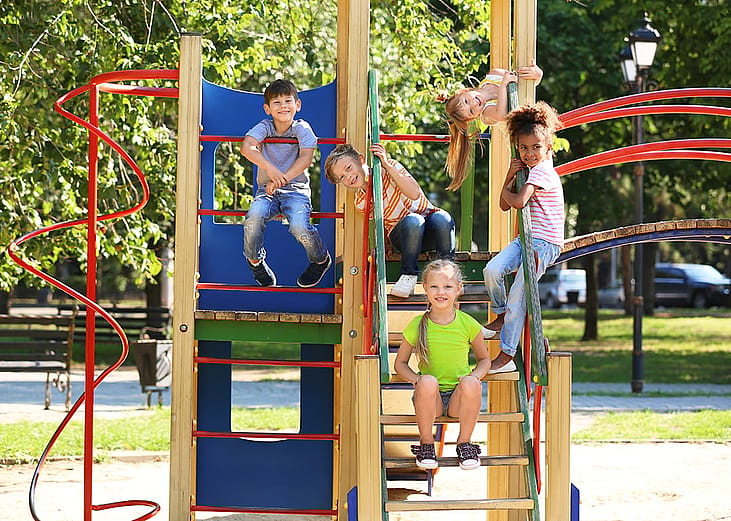 Children posing for a photo after playing in an outside playground.