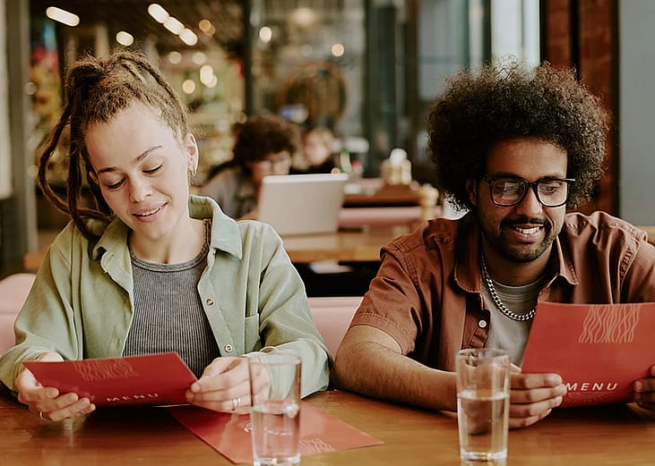A young couple looking at a restaurant menu on their date.
