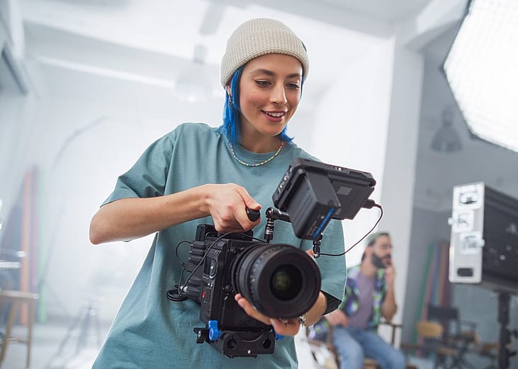 A young female cinematographer working a camera in a studio.