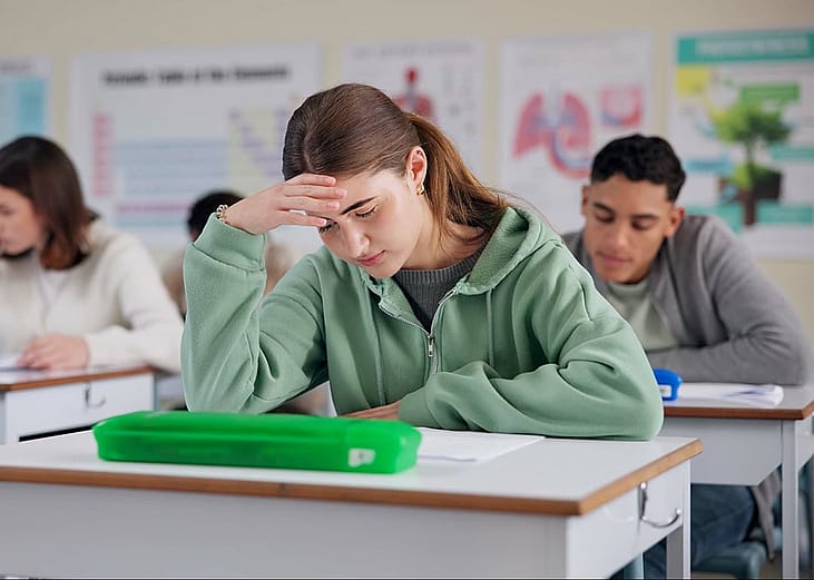 A young female student stressed about an exam inside the classroom.
