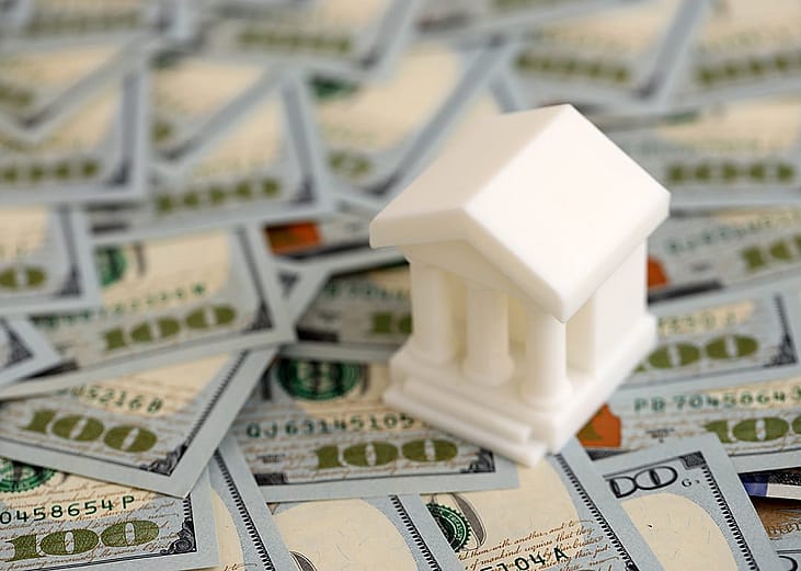 A miniature bank placed on US dollar bills, representing banking loan for business concepts.