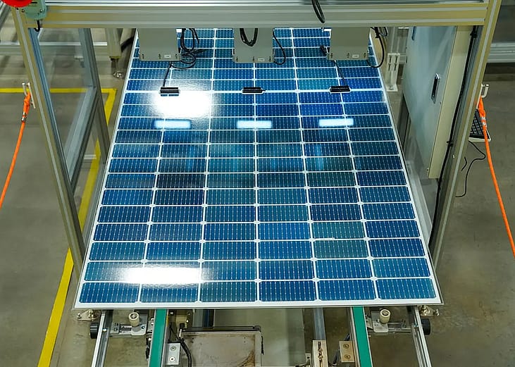 A photovoltaic (PV) solar panel moving along an automated factory assembly line.