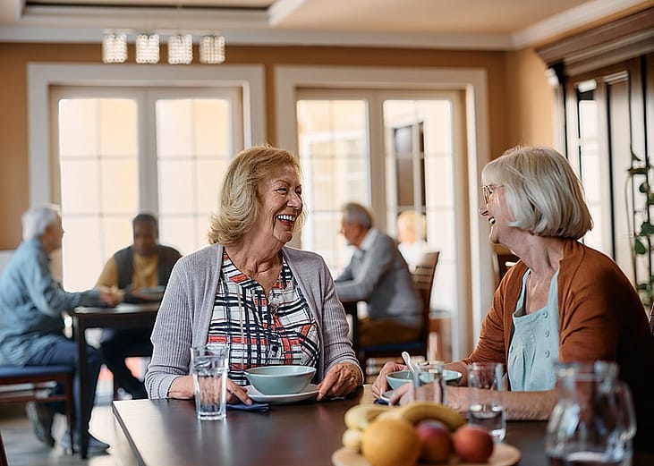 Elderly people enjoying a good conversation in the dining area of a nursing home.