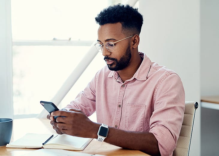 A businessman texting on his phone in an office.