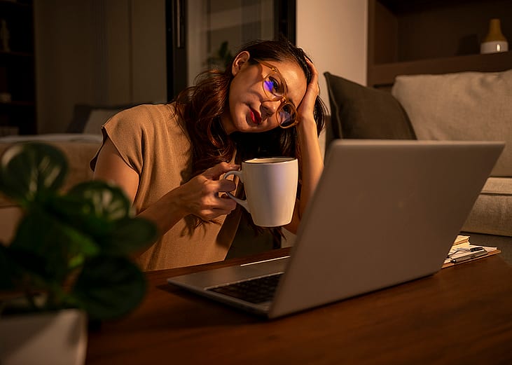 A woman feeling stressed from overworking at night.
