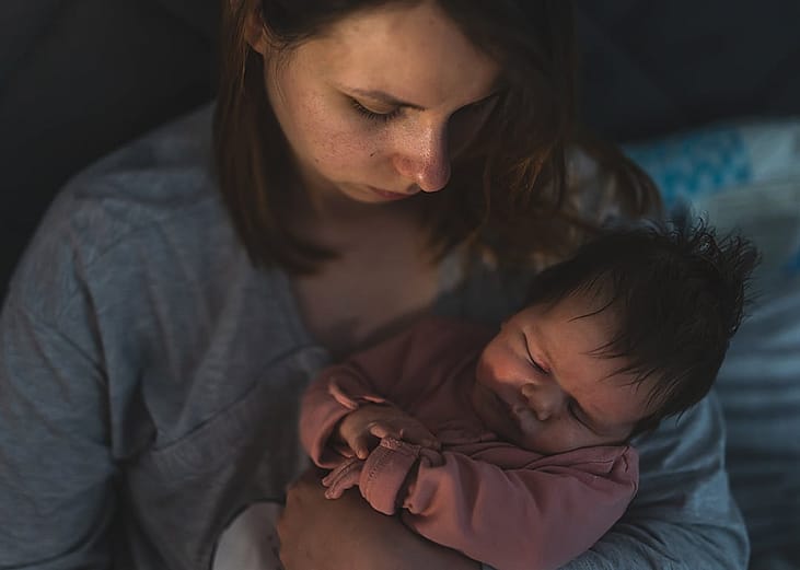 A young mother putting her newborn to sleep at night.