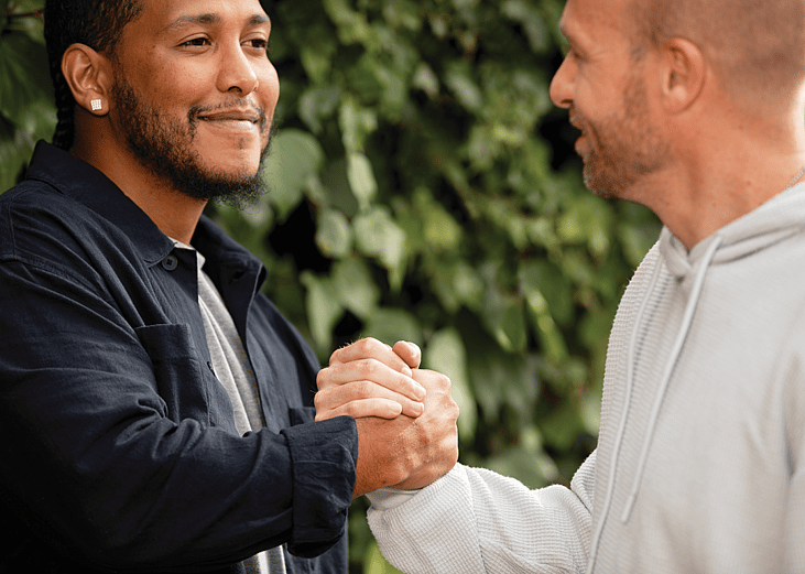Two men greeting each other with a handshake outdoors