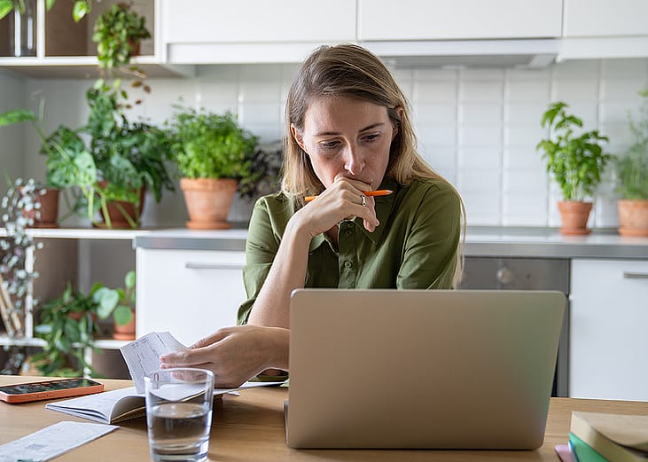 A pensive woman reviewing bills at home.