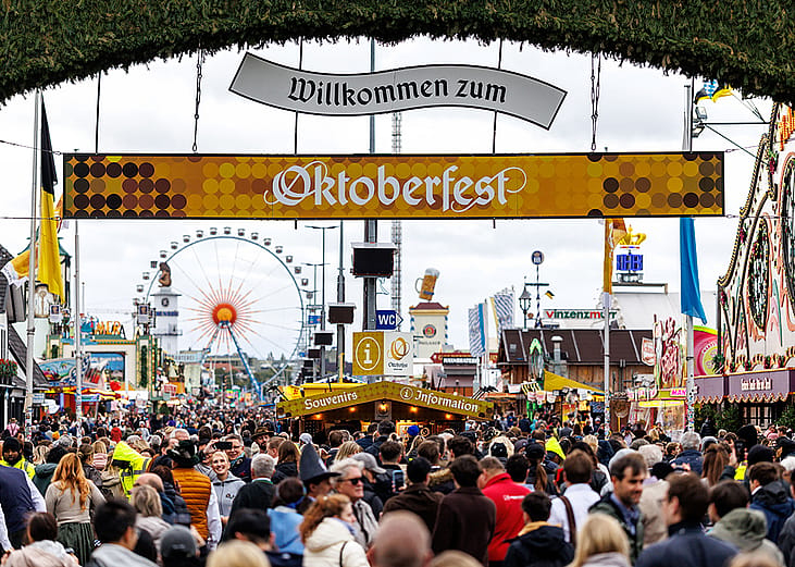 Numerous visitors walk through the gate from the main entrance to the 190th Oktoberfest on the Theresienwiese in Munich, Germany.